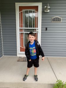 Young boy in front of home, ready for school
